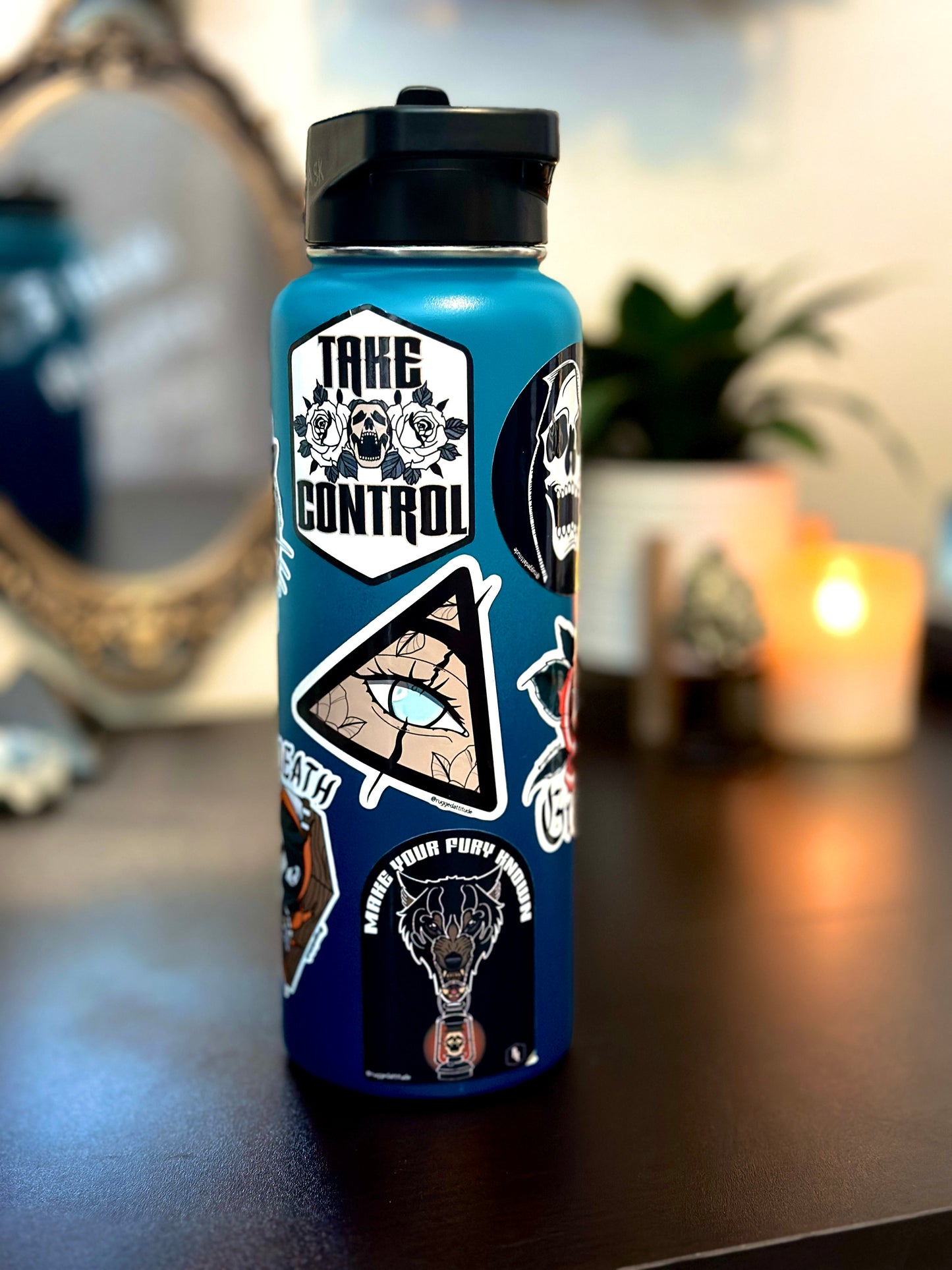 2x3 inch die cut sticker displayed on water bottle in an aesthetic office desk with a design of a wolf holding a lantern and the gothic calligraphy words "make your fury known". Branded with Rugged Attitude logo and paired with several other branded stickers.